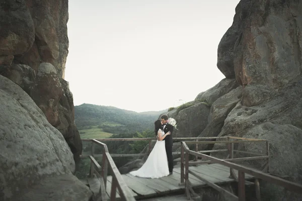 Vacker brud, brudgum kyssas och kramas nära klipporna med fantastisk utsikt — Stockfoto