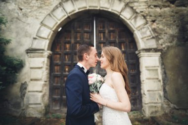 Güzel, romantik bir düğün. Yeni evliler. Eski kalenin yakınlarında sarılıyorlar.