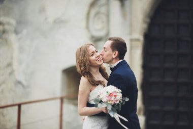 Güzel, romantik bir düğün. Yeni evliler. Eski kalenin yakınlarında sarılıyorlar.