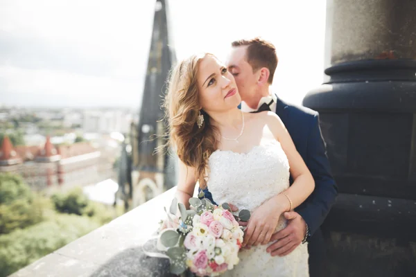 Stílusos szép esküvői pár csók és ölelés a háttérben panorámás kilátás nyílik az óvárosra — Stock Fotó