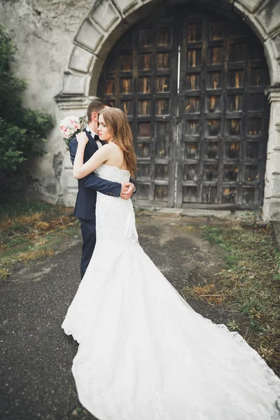 Feliz boda pareja abrazándose y sonriendo el uno al otro en el fondo viejo castillo — Foto de Stock