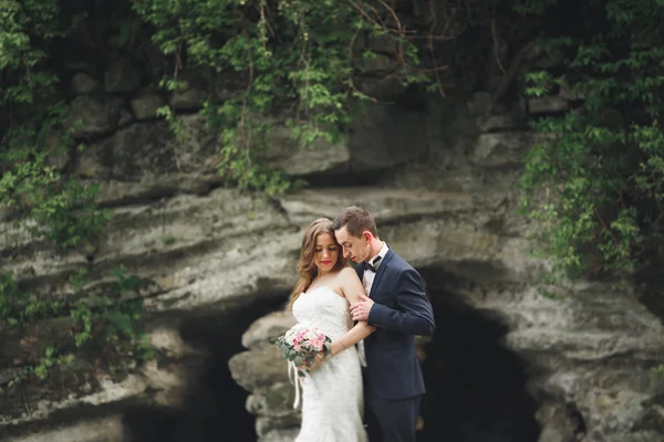 Glückliches Hochzeitspaar umarmt und lächelnd einander auf dem Hintergrund herrliche Pflanzen im Schloss — Stockfoto