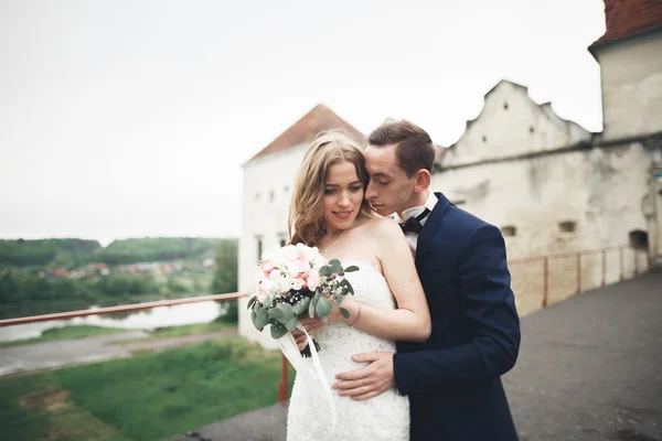 Szczęśliwy wesele para przytulanie i uśmiechając się nawzajem na tle starego zamku — Zdjęcie stockowe