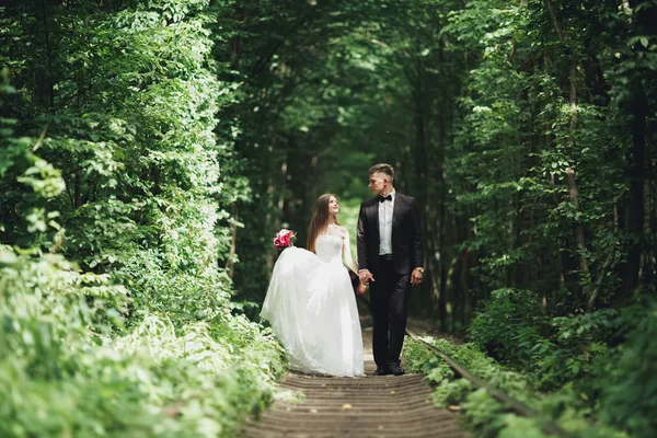 Casal de casamento jovem, noiva e noivo posando em uma trilha ferroviária — Fotografia de Stock
