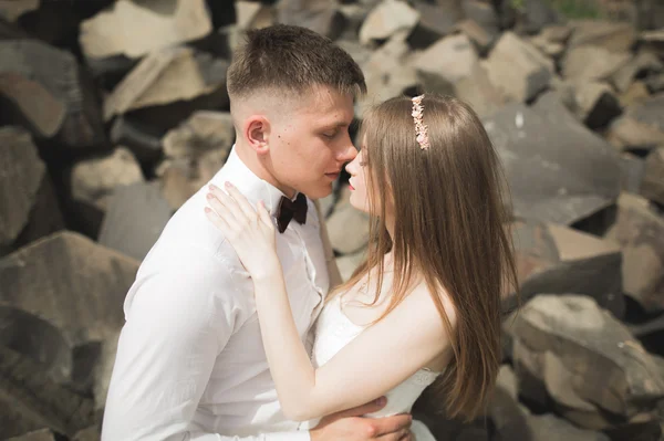 Bruiloft koppel in liefde kussen en knuffelen in de buurt van rotsen op prachtig landschap — Stockfoto