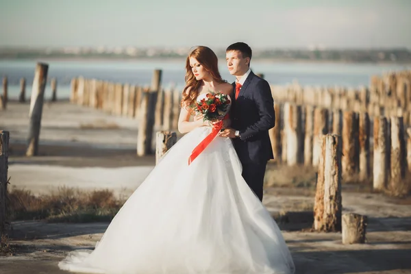 Güzel genç düğün çift, gelin ve damat arka plan denizde ahşap direklerin yakın poz — Stok fotoğraf