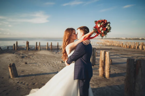 Elegante pareja de boda feliz elegante, novia, magnífico novio en el fondo del mar y el cielo — Foto de Stock