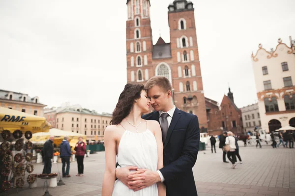 クラクフの中央広場を歩いてエレガントな美しい結婚式のカップル — ストック写真