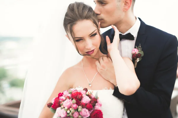 Beautiful couple, bride and groom posing on balcony with backgrounf of old city — Stock Photo, Image