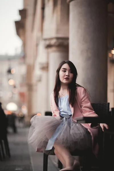 Linda modelo de menina asiática em vestido sentado no fundo da cidade velha — Fotografia de Stock