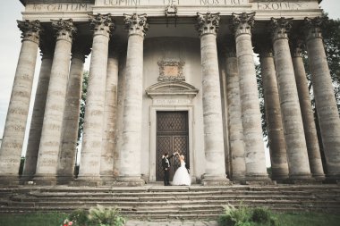 Güzel, romantik bir düğün. Yeni evliler. Eski kalenin yakınlarında sarılıyorlar.
