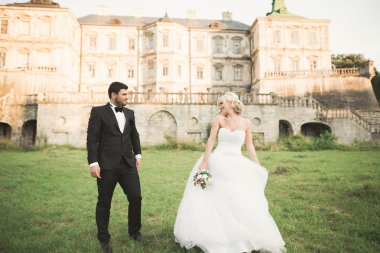 Güzel, romantik bir düğün. Yeni evliler. Eski kalenin yakınlarında sarılıyorlar.