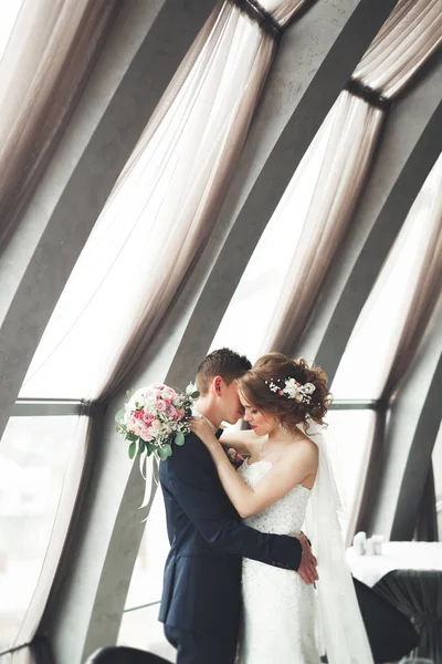 Frisch verheiratetes Hochzeitspaar posiert und Braut hält Blumenstrauß in Händen — Stockfoto