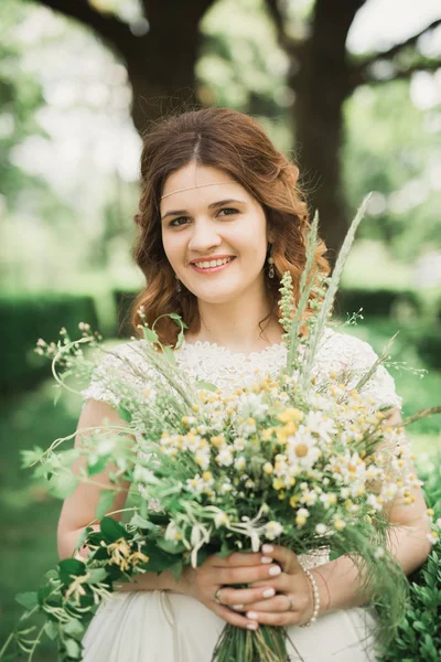 Hermosa novia joven de lujo en vestido de novia posando en el parque — Foto de Stock