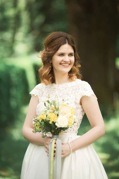 Indah pengantin muda mewah dalam gaun pengantin berpose di taman — Stok Foto