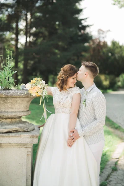 Casal elegante de recém-casados felizes andando no parque em seu dia de casamento com buquê — Fotografia de Stock