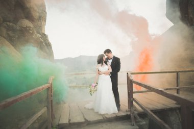 Çift yakınındaki kayaların arkasında renkli duman ile poz düğün