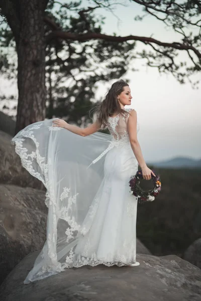Magnifique mariée en robe élégante tenant bouquet posant près de la forêt — Photo
