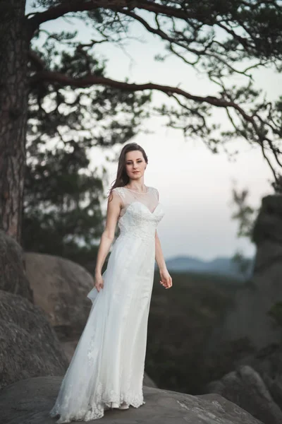 Preciosa novia en vestido elegante celebración ramo posando cerca del bosque — Foto de Stock