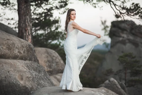 Magnifique mariée en robe élégante tenant bouquet posant près de la forêt — Photo