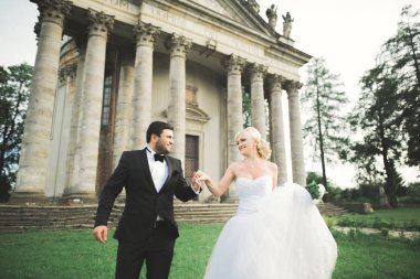 Güzel, romantik bir düğün. Yeni evliler. Eski kalenin yakınlarında sarılıyorlar.