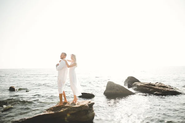 Casal amoroso romântico posando em pedras perto do mar, céu azul — Fotografia de Stock