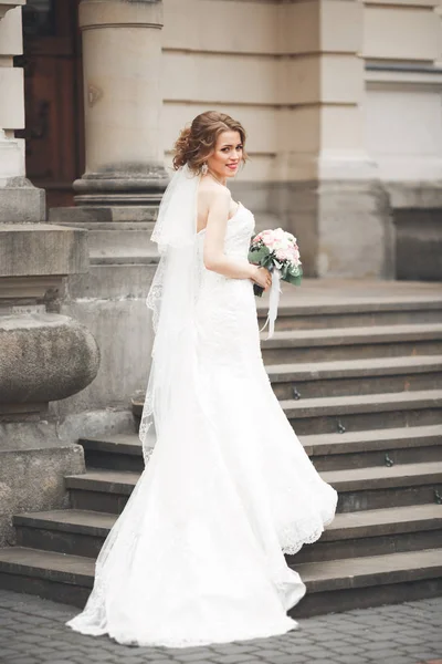 Maravillosa novia con un lujoso vestido blanco posando en el casco antiguo —  Fotos de Stock