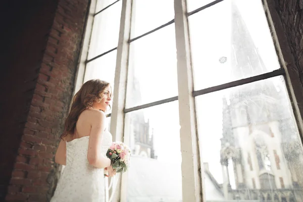 Elegante bella sposa nuziale posa vicino grande arco della finestra — Foto Stock