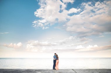 Güzel sevgi dolu çift, gurur iskelede yürüyüş uzun elbise ile