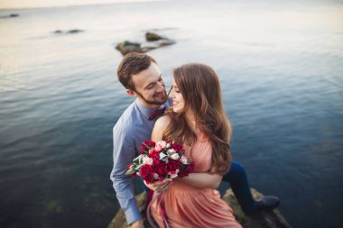 Mavi Denizi çevresinde büyük bir taş üzerinde oturan Düğün çifti