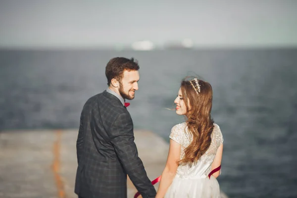 Sposi appena sposati che camminano sulla spiaggia al tramonto . — Foto Stock