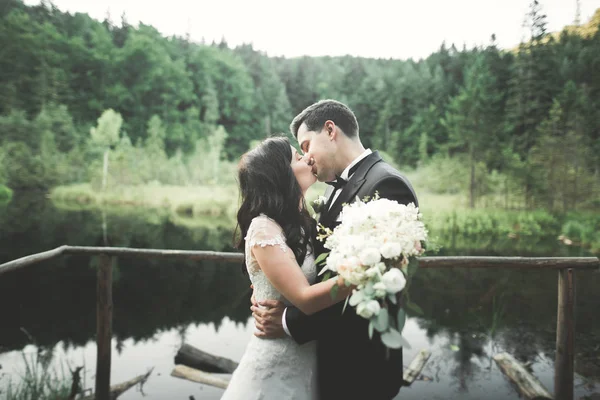 Encantadora novia, elegante novio en paisajes de montañas y puesta de sol en el lago. Hermosa pareja de boda —  Fotos de Stock