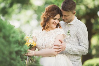 Güzel romantik bir çift yeni evliler gün batımında parkta sarılıyorlar.