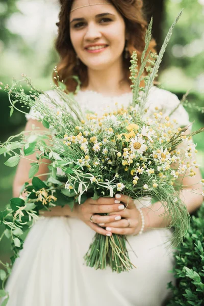 La novia sosteniendo ramo de flores en el parque. Boda — Foto de Stock