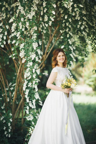 La novia sosteniendo ramo de flores en el parque. Boda — Foto de Stock