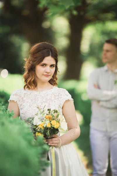 Novia posando y sonríe mientras el novio espera en el fondo — Foto de Stock