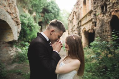 Güzel, romantik bir düğün. Yeni evliler. Eski kalenin yakınlarında sarılıyorlar.