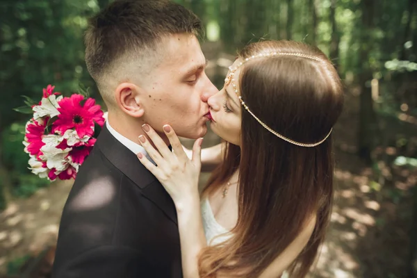 Hermosa joven pareja de boda se besa y sonríe en el parque — Foto de Stock