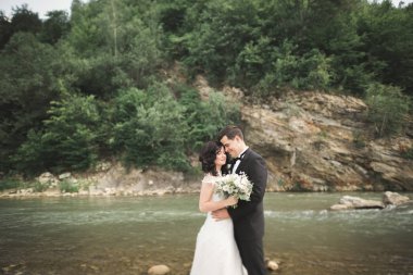 Zarif nazik şık damat ve gelin taşlarla Nehri yakınında. Evlilik çift aşık