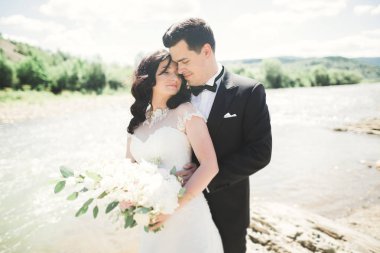 Gelin ve damat güzel düğün buket tutarak. Nehir kenarında poz