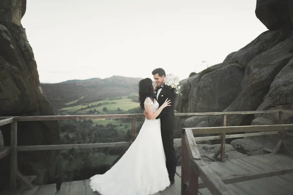 結婚式のカップルで愛キスと抱擁近くの岩で美しい風景 — ストック写真