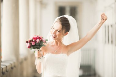 Lüks bir gelin, bir kız buketle poz veriyor ve gülümsüyor.