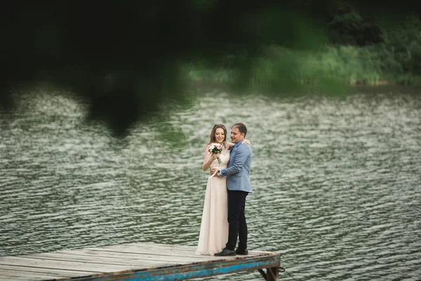 花嫁と花婿、川の上を歩いて、笑って、キス — ストック写真