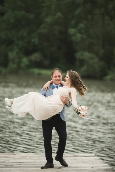 Novio llevando novia cerca del lago y el bosque —  Fotos de Stock