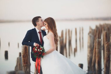 Çift düğün, damat, gelin buketi günbatımı üzerinde denize yakın poz ile