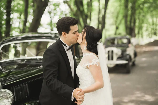 Felice coppia di sposi, uomo e moglie baciare vicino elegante auto retrò — Foto Stock