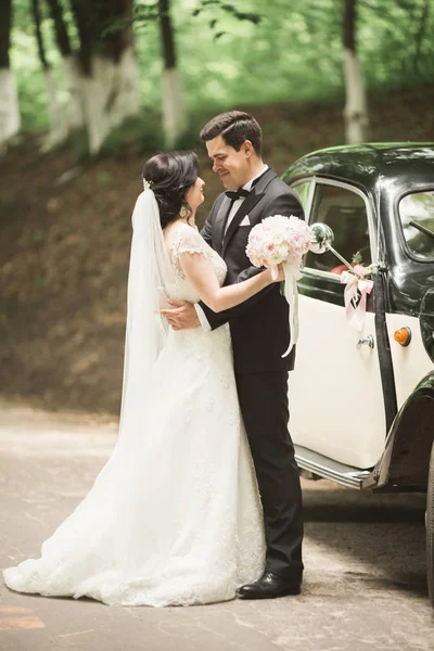 Belo casal recém-casado posando perto de carro preto retro — Fotografia de Stock