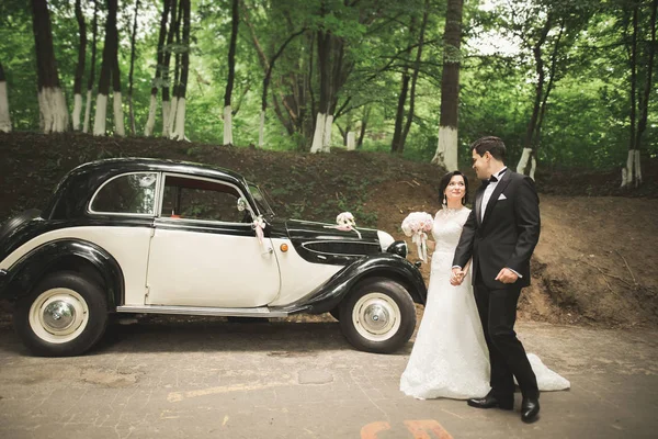 Szczęśliwy newlywed para, mężczyzna i żona Całowanie w pobliżu stylowe retro samochodów — Zdjęcie stockowe