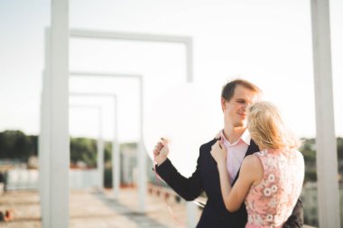 Çatıda mükemmel şehir manzaralı elele ve sarılma poz aşık genç bir çift. Güzel gün batımı