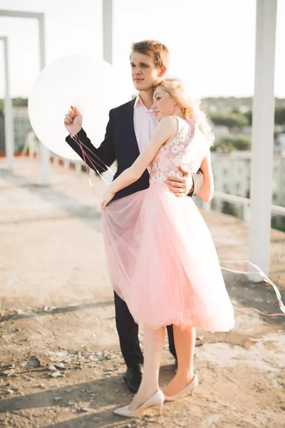 Jeune couple amoureux posant sur le toit avec vue parfaite sur la ville tenant la main et étreignant. Beau coucher de soleil — Photo